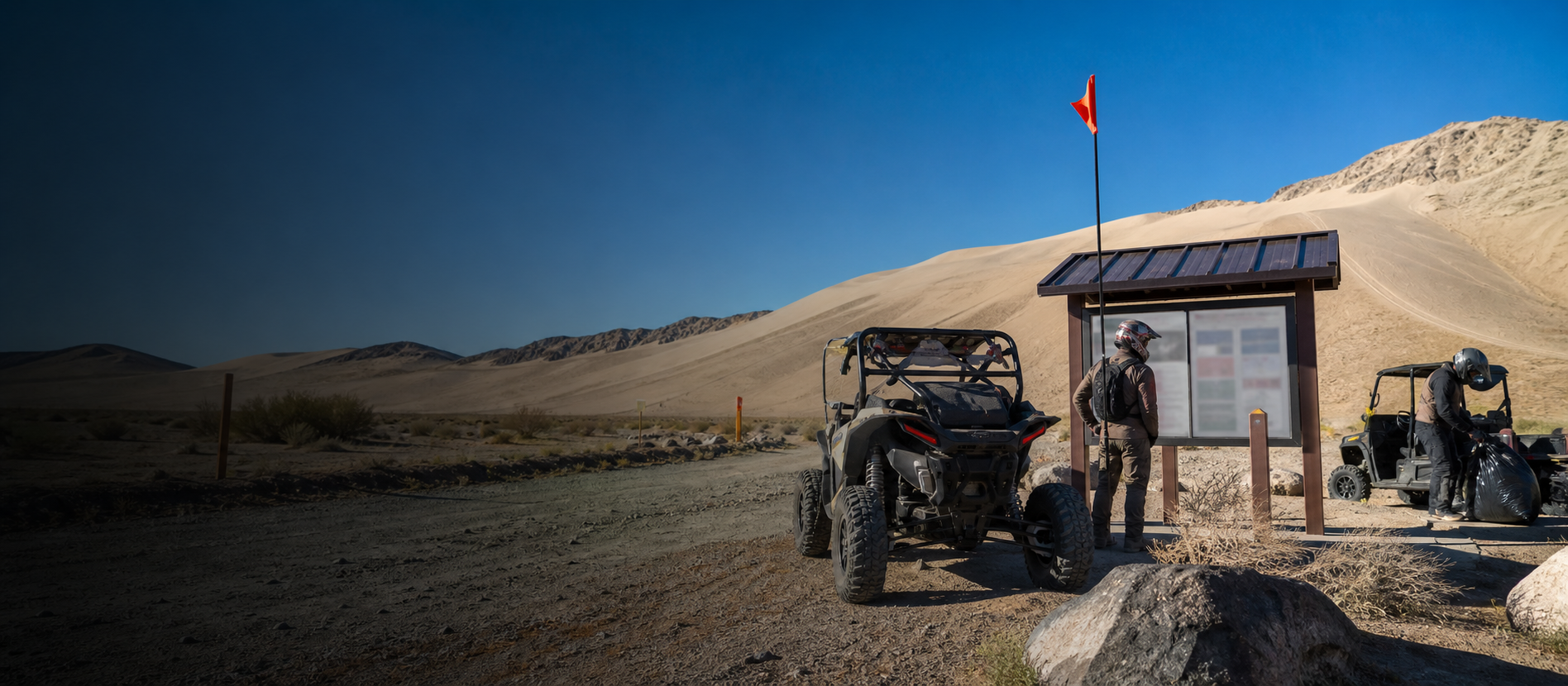 Visitors checking official information and securing camp trash before riding at Sand Mountain