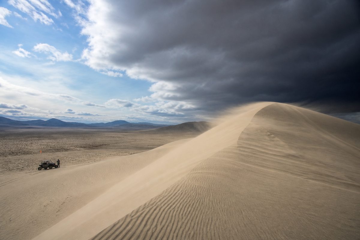 Wind lifting sand off the crest of Sand Mountain and flattening visibility across the dune face